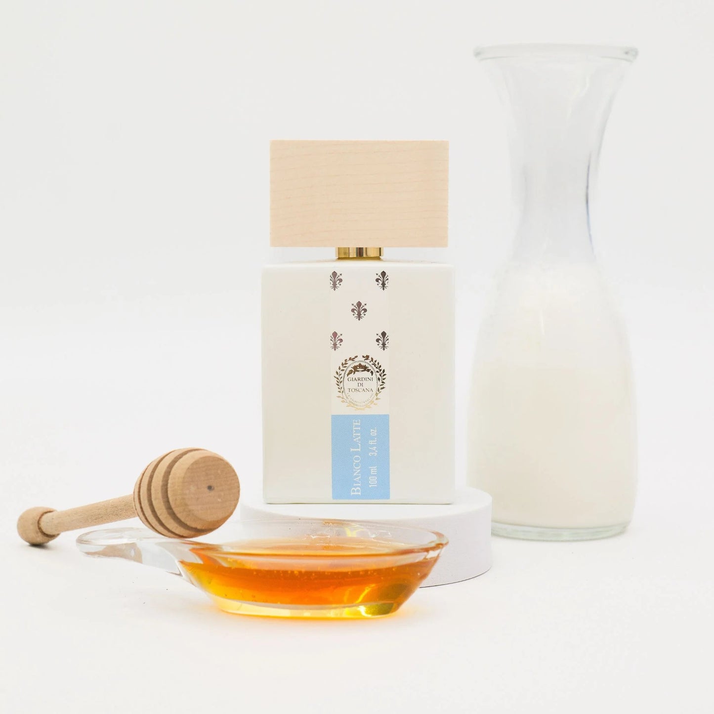 Honey bottle with wooden dipper and glass container on a white background