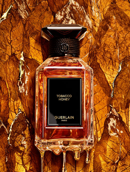Guerlain Tobacco Honey perfume bottle on a textured tobacco leaf background