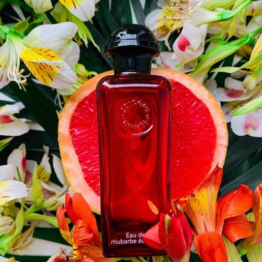 Red perfume bottle on a grapefruit with flowers in the background