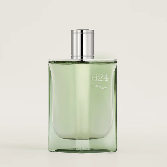 Green perfume bottle with silver cap on a light gray background